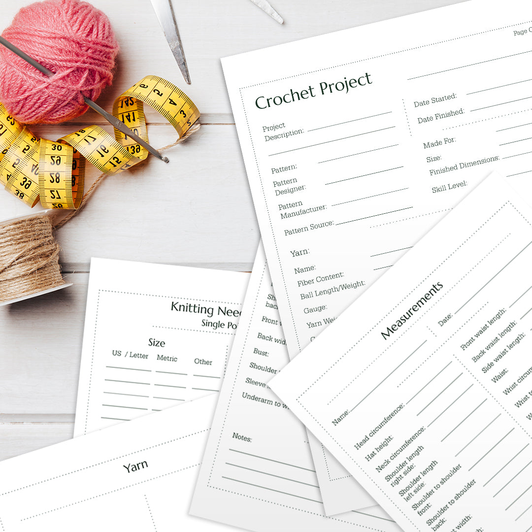 Image of various Crochet Journal sheets, a ball of pink yarn, a measuring tape, and twine on a white wooden surface.