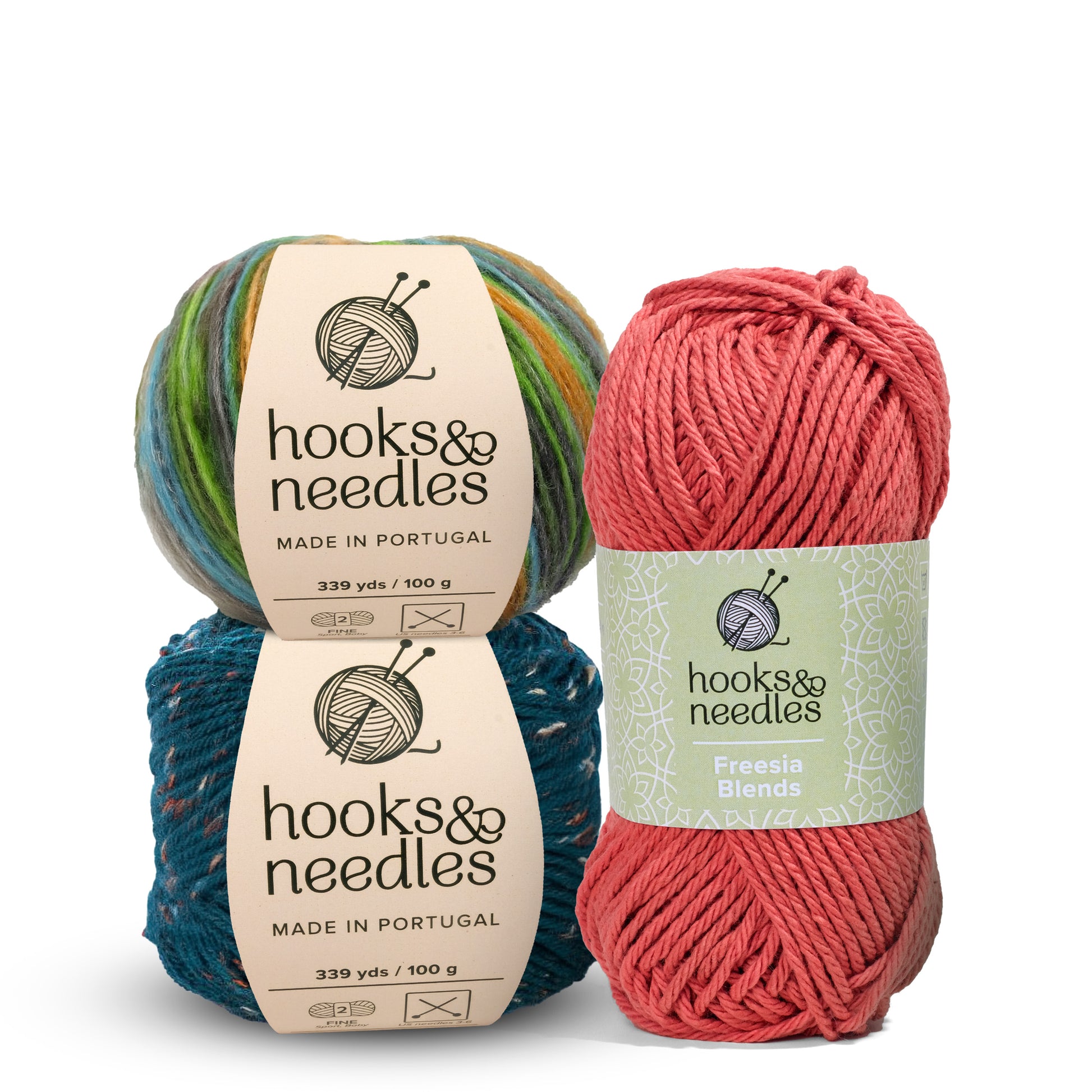 Three skeins from the Hooks & Needles Only Yarn Subscription Box: two 100g skeins in green and blue hues, and one 100g skein in a pink shade labeled Freesia Blends.