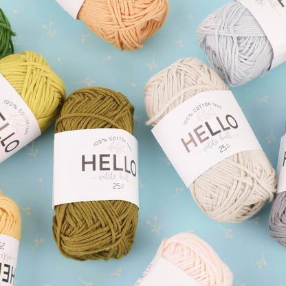 Assorted yarns in various colors, part of the "Amigurumi Subscription Box," laid out on a light blue surface.