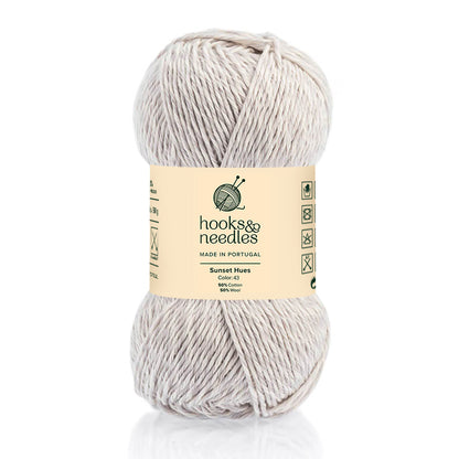 A skein of Sunset Hues Yarn 50g, cream-colored and sustainable, made in Portugal from a 50% cotton, 50% viscose blend, displayed against a white background.